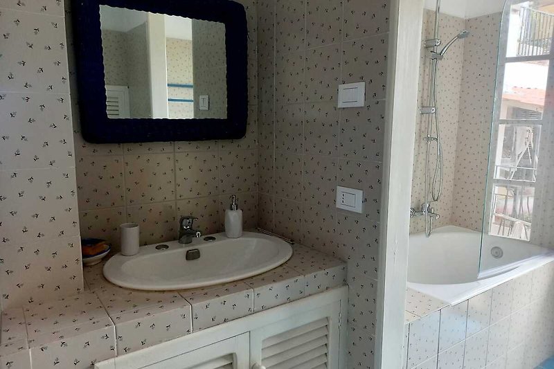 Badezimmer mit lila Akzenten, großer Spiegel und Badewanne.