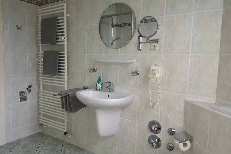 Badezimmer mit Spiegel, Waschbecken und lila Fliesen.