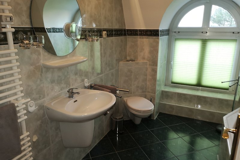 Schönes Badezimmer mit Spiegel, Waschbecken und Fenster.