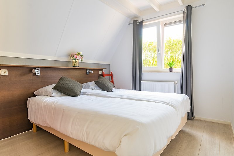 Stijlvolle slaapkamer op de begane grond met comfortabel bed en afzonderlijk bedienbare verlichting.