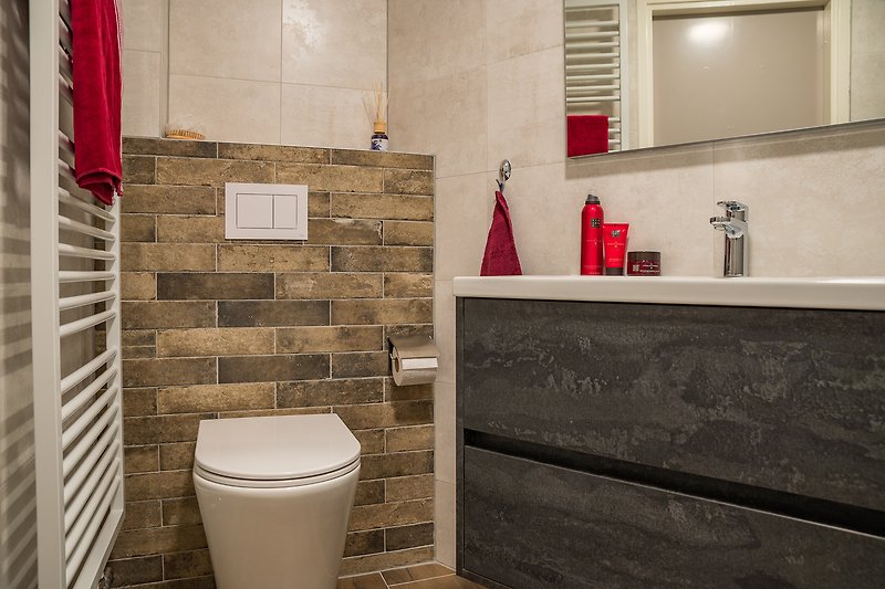Moderne badkamer met vrijdragend toilet, handdoekradiator en wastafelmeubel