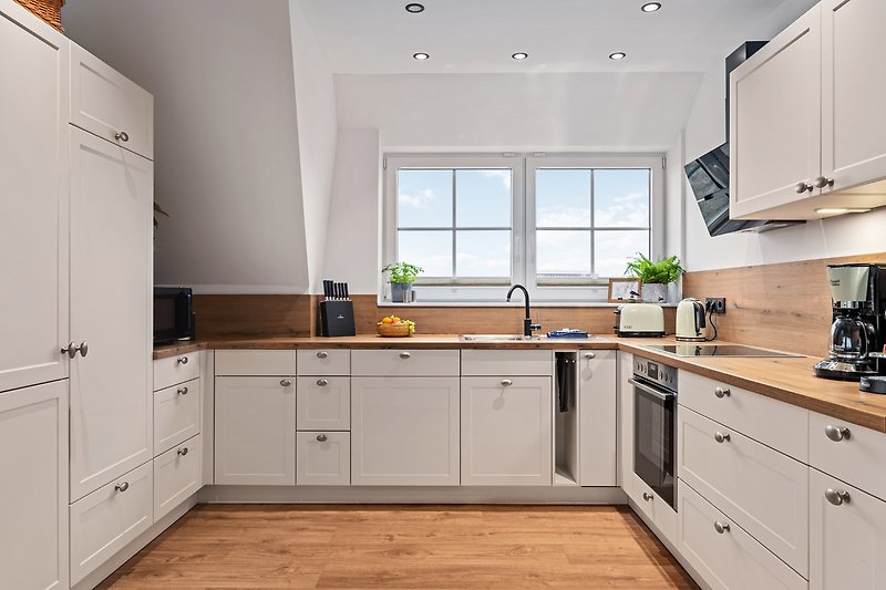 Moderne Küche mit Holzschränken, Arbeitsplatte und Fenster FeWo Ostseeblick
