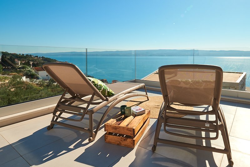 Ein sonniger Balkon mit bequemen Möbeln und Blick auf den See.