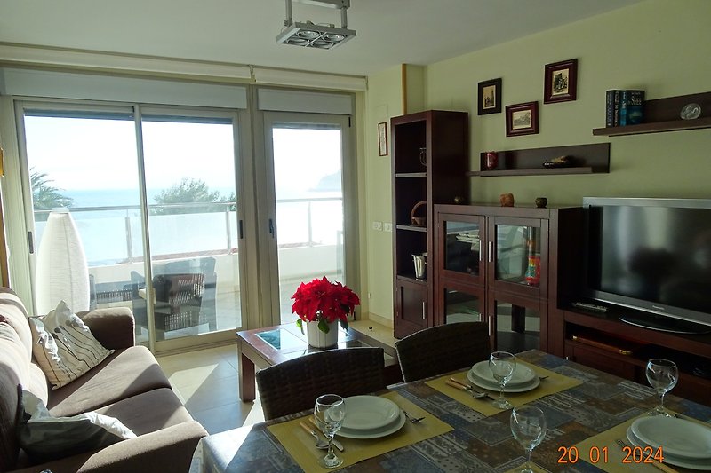 Een comfortabele woonkamer met stijlvol meubilair en veel natuurlijk licht, zeezicht en toegang tot groot terras