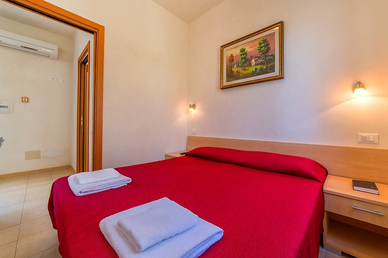 Un'abitazione con arredamento confortevole, legno e tessuti, con un letto e una lampada.