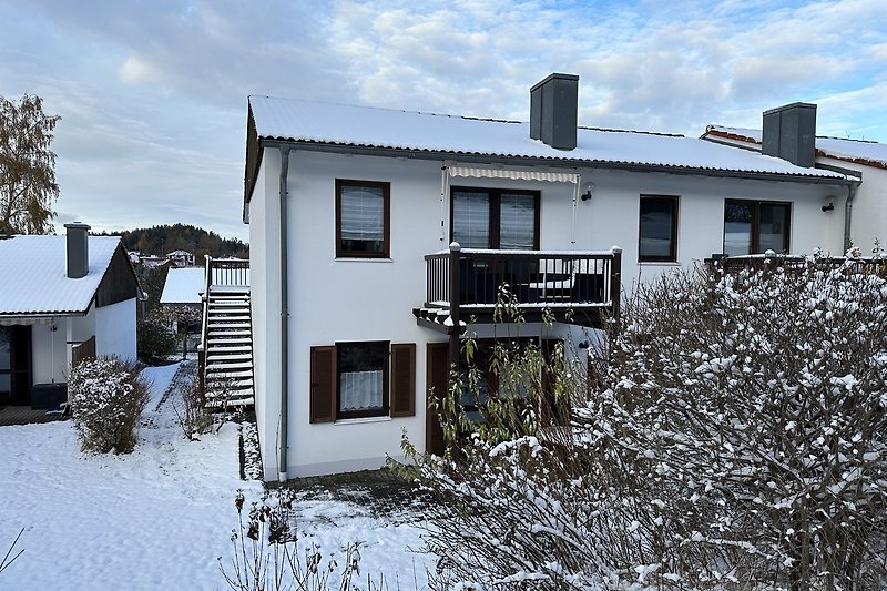 Ein charmantes Haus mit schneebedecktem Dach und malerischer Umgebung.