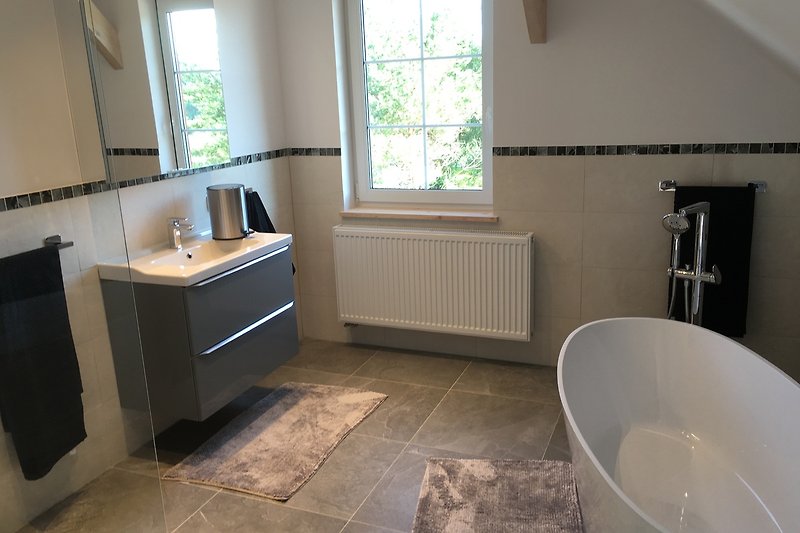 Modernes Bad mit graumarmorierten Fliesen, Badewanne, Dusche und WC