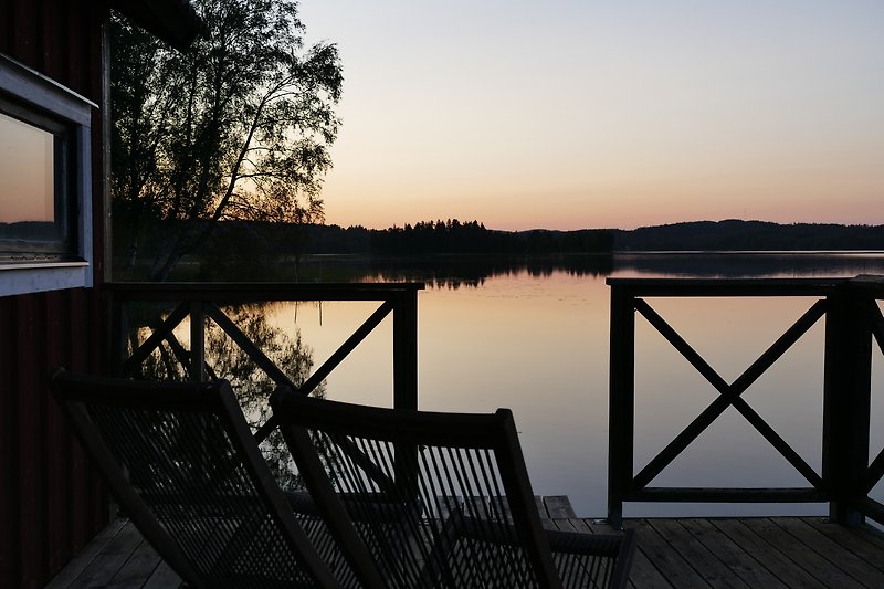 A tranquil lake at sunset, with a wooden dock and a beautiful sky.