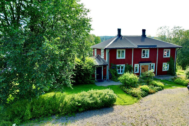 A charming cottage surrounded by lush greenery and a picturesque natural landscape.