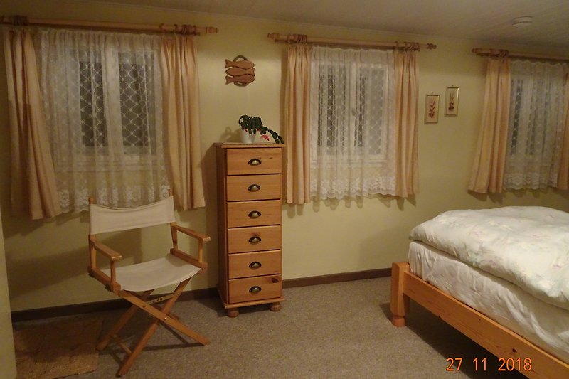 Schlafzimmer 1 mit Holzmöbeln und Vorhängen.