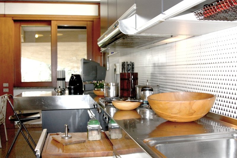 Una cucina con elettrodomestici, mobili in legno e un lavello.