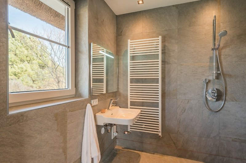 Ein stilvolles Badezimmer mit Holzboden, Waschbecken und Fenster.