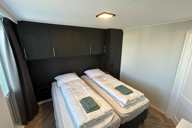 Gemütliches Schlafzimmer mit Holzbett und hochwertiger Bettwäsche.