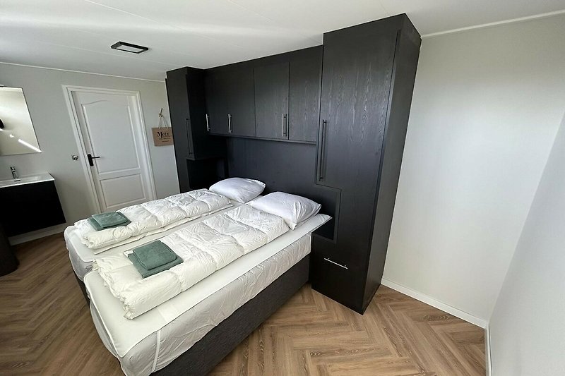 Komfortables Schlafzimmer mit Holzbett und hochwertiger Bettwäsche.