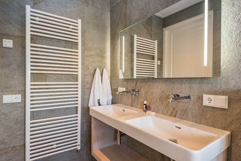 Ein stilvolles Badezimmer mit Spiegel, Waschbecken und Holzboden.