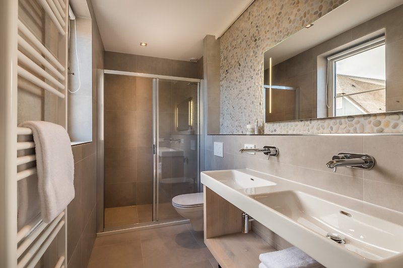 Modernes Badezimmer mit Spiegel, Waschbecken und stilvoller Armatur.