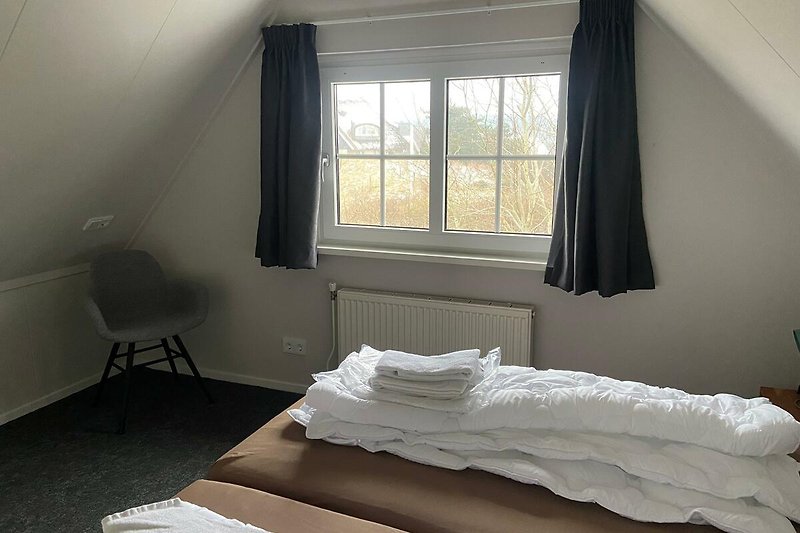 Gemütliches Schlafzimmer mit Holzmöbeln und weißer Bettwäsche.