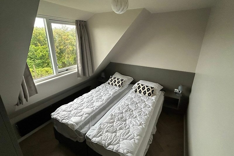 Gemütliches Schlafzimmer mit Holzboden, großem Fenster und bequemem Bett.
