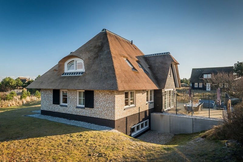 Ein charmantes Landhaus mit einem strohgedeckten Dach und einem malerischen Garten.