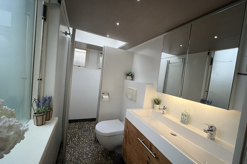 Badezimmer mit Spiegelkasten, Waschbecken und Armatur.