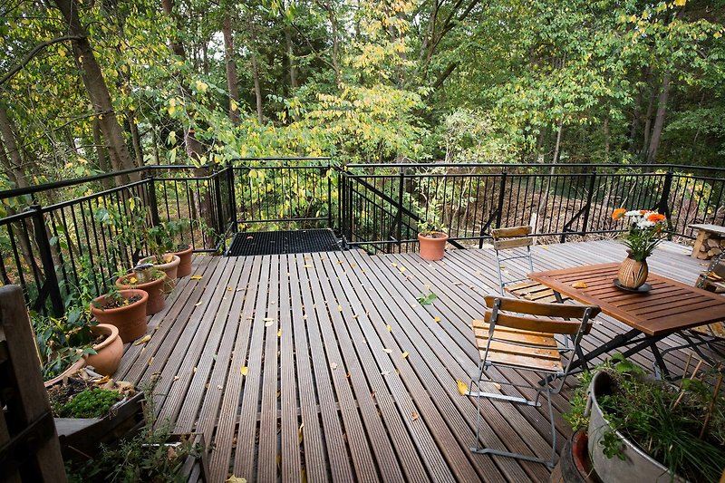 Einladende Terrasse mit Holzmöbeln und grünen Pflanzen.