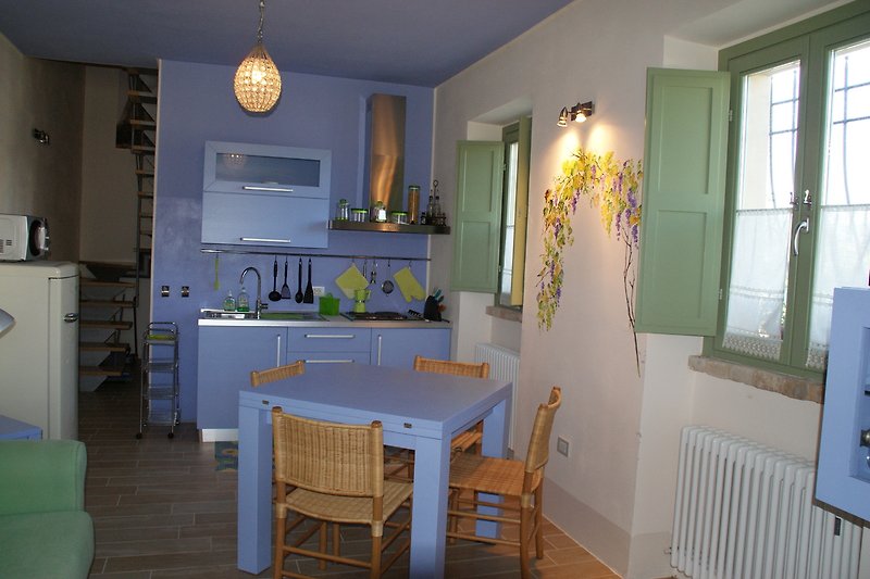 Moderne Küche mit Holzmöbeln, blauer Wand und Fenster. Gemütlicher Essbereich.