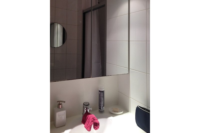 Modernes Badezimmer mit grauem Fliesenboden, Spiegel und Waschbecken.