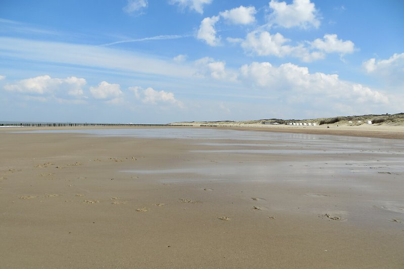 Strand mit blauem Meer, Sand und Wellen.