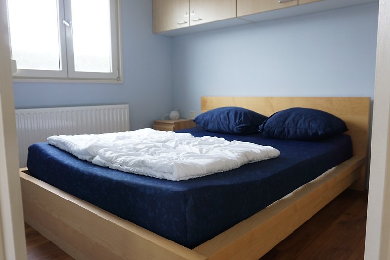 Comfortabele slaapkamer met houten bed en blauwe accenten.