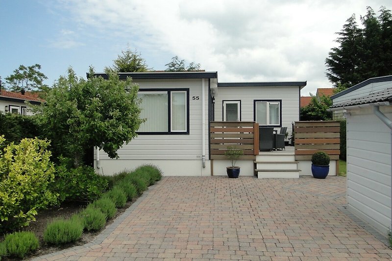 Prachtig huis met tuin, garage en oprit, omgeven door groen en blauwe lucht.