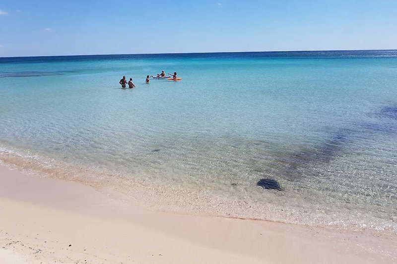 Strand am Ionischem Meer, azurblauem Wasser und entspannten Urlaubern.