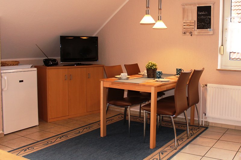 Gemütliches Wohnzimmer mit Holzmöbeln, Tisch und Fernseher.