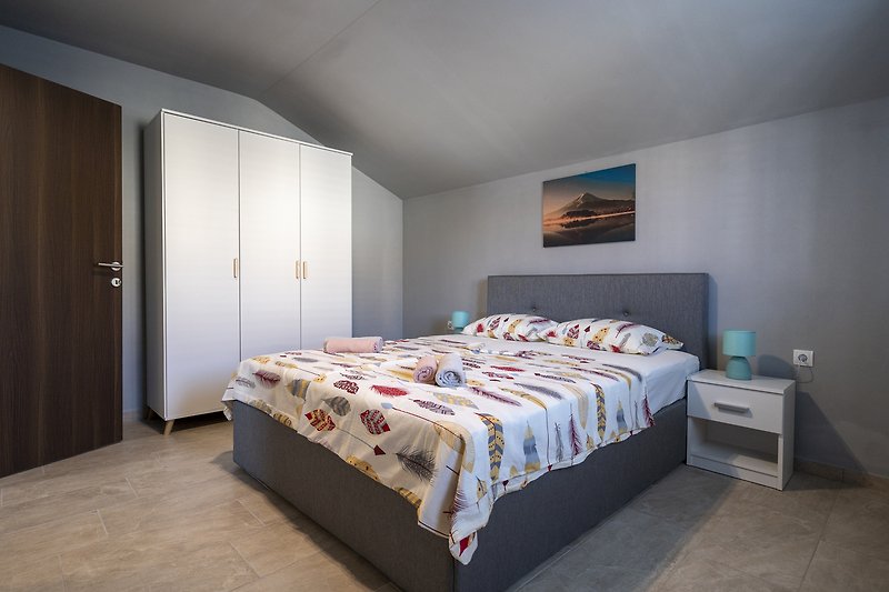 Udobna spavaća soba s drvenim krevetom i udobnim namještajem.