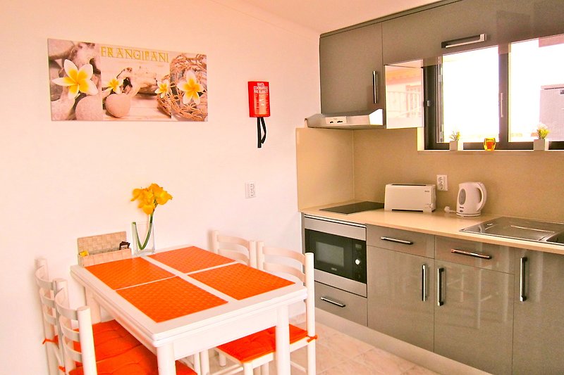 Stylish kitchen with orange accents, wooden furniture, and modern appliances.