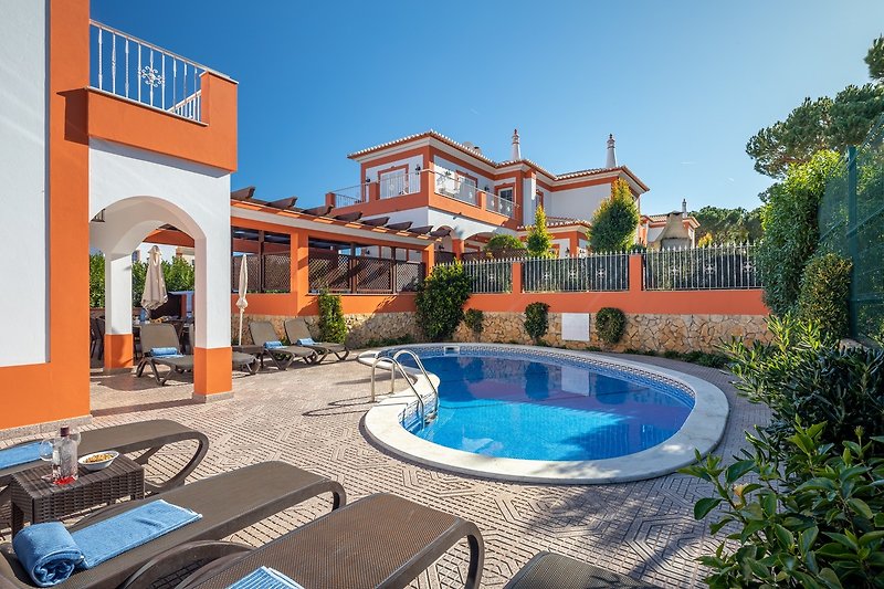 Stunning seaside resort with azure water, swimming pool, and outdoor furniture.