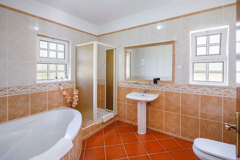 Modern bathroom with elegant fixtures, mirror, bathtub, and window.