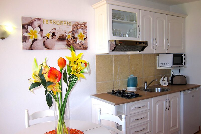 Cozy kitchen with beautiful flowers, modern cabinetry, and elegant furniture.