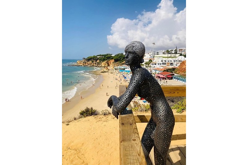 A coastal paradise with sandy beaches, clear blue water, and a stunning bronze sculpture.