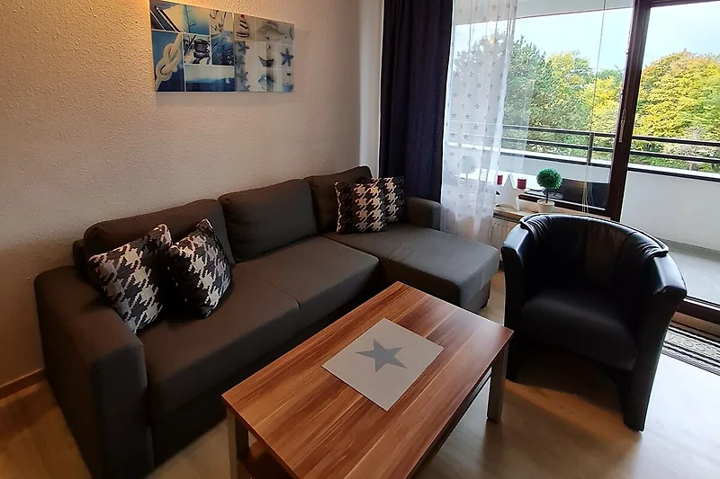 Gemütliches Wohnzimmer mit Holzmöbeln, Couch und Fensterblick.