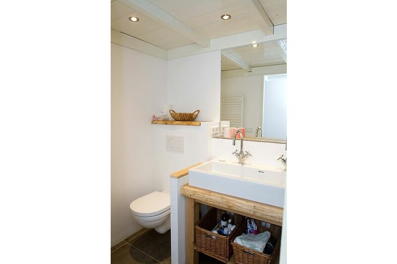 Moderne badkamer met houten meubels, spiegel en wastafel.
