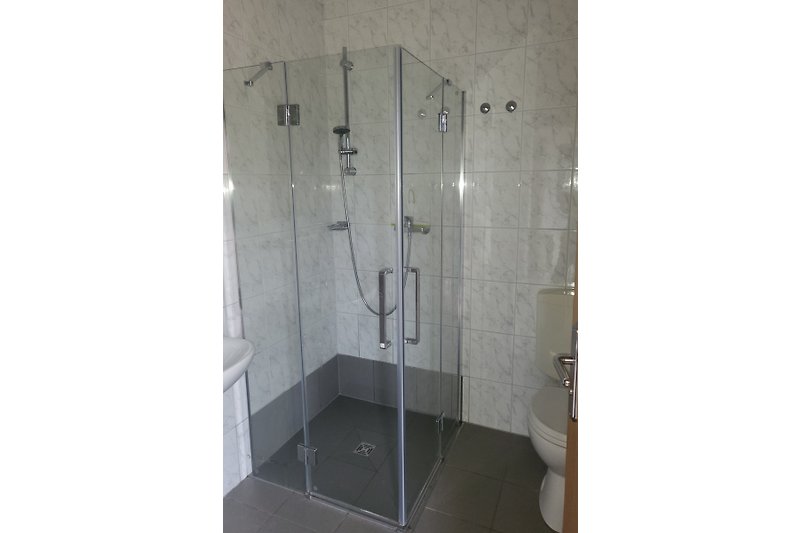 Schönes Badezimmer mit Dusche, Fliesen und eleganten Armaturen.