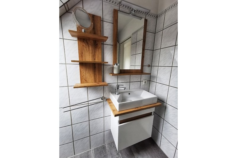 Schönes Badezimmer mit Spiegel, Waschbecken und Holzakzenten.