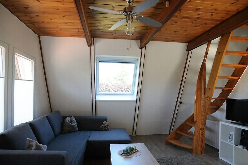 Gemütliches Wohnzimmer mit Holzbalken und bequemer Couch.
