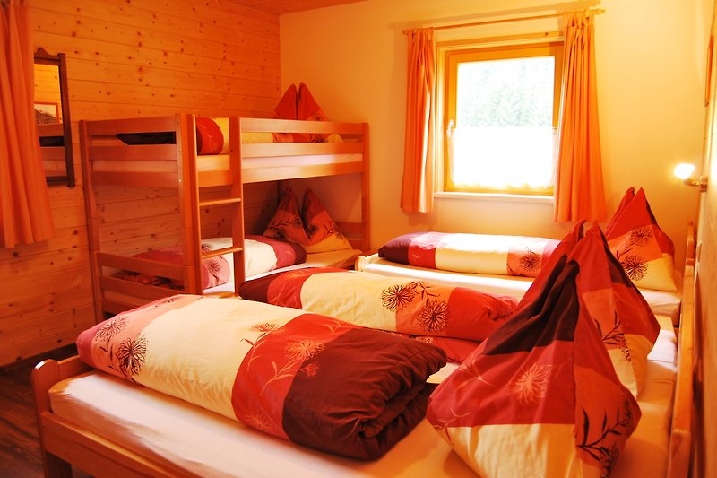 Schlafzimmer mit Holzmöbeln, orangenen Akzenten und gemütlicher Bettwäsche.