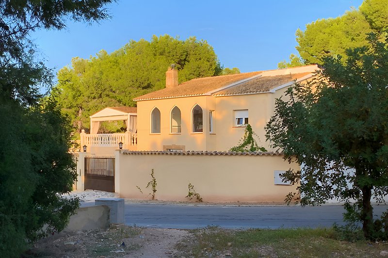 Une villa méditerranéenne avec des éléments arabes, située dans une zone boisée.