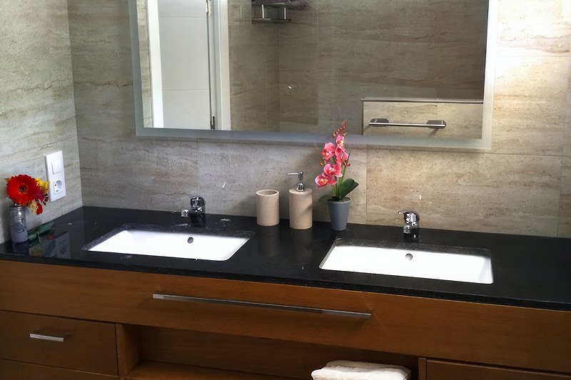 Salle de bain de luxe avec double lavabo, miroir chauffant, toilette suspendue et douche à effet pluie.