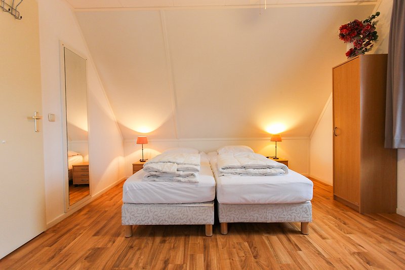 Comfortabele slaapkamer met houten meubels en warme verlichting.