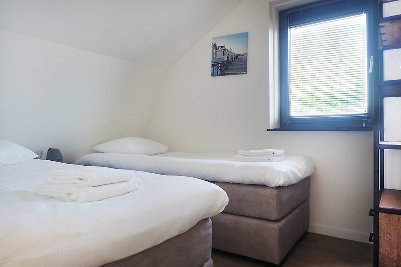 Schlafzimmer mit gemütlichem Bett, Fenster und Holzdecke.