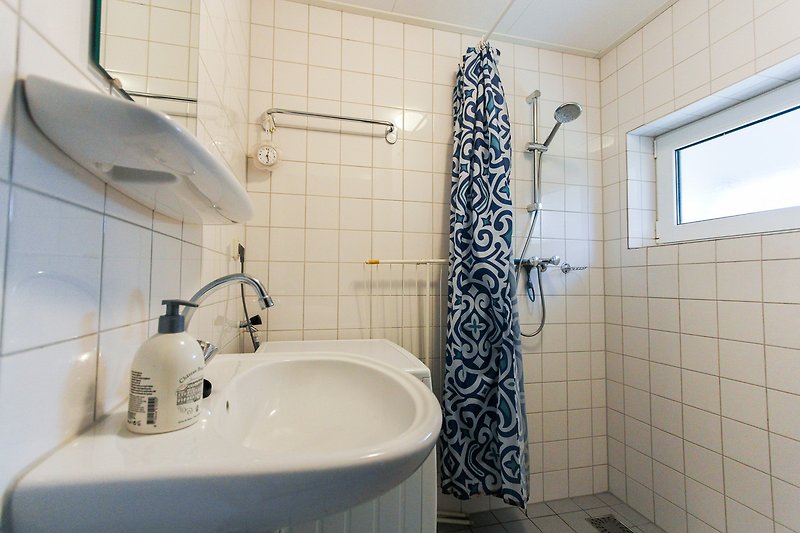 Moderne badkamer met paarse accenten, spiegel en glazen douchekop.