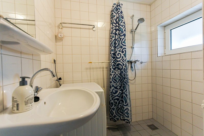 Mooie badkamer met paarse accenten, spiegel en wastafel.